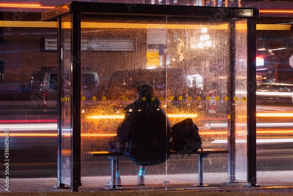 Fototapeta passing buss and a man sitting in a bus stop 