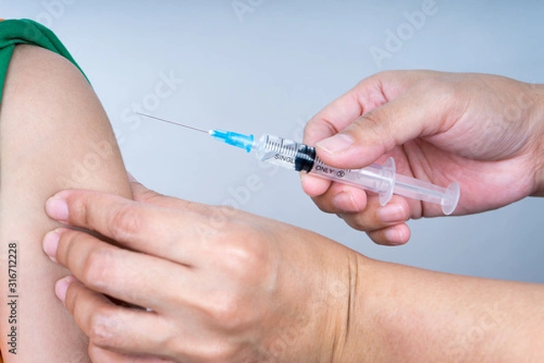 Fototapeta Syringe with needle facing towards boy arm for injection. 