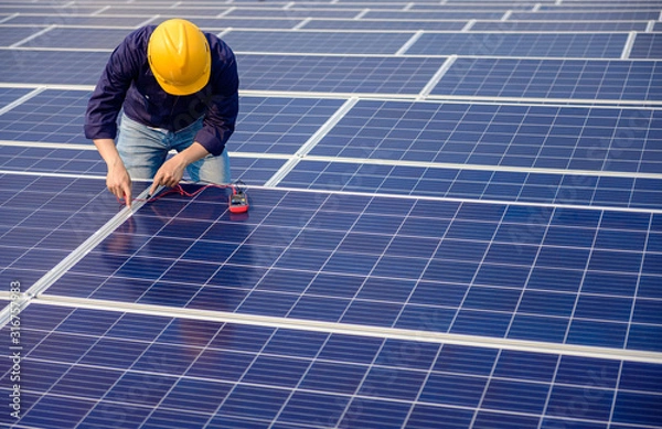 Fototapeta Electrician working on measurement Voltage at solar cell on building roof ,  Renewable energy Concept.