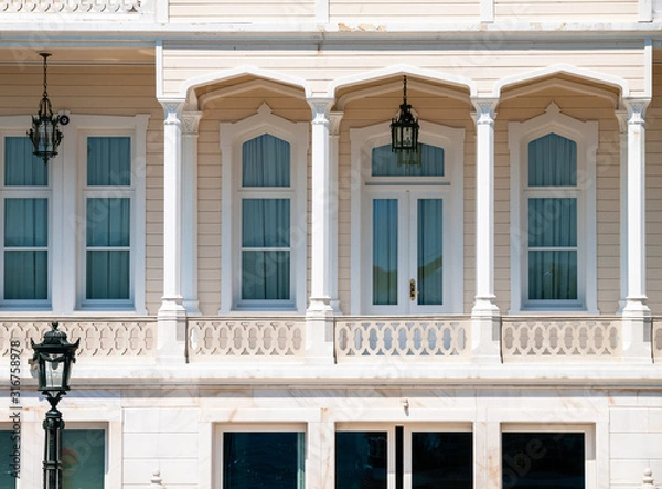 Fototapeta Wooden mansion close up detail. Beautiful classic architecture balcony with arch  columns and many windows.