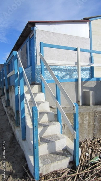 Fototapeta Steps leading from the beach to the cabins by the sea in blue and white.