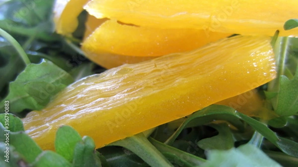 Fototapeta A close-up of pieces of yellow pepper cut into strips on a rocket salad. 