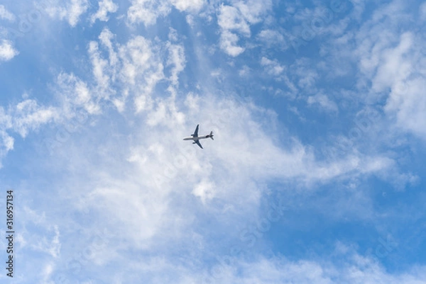 Fototapeta Airplane in the sky. The passenger plane in front of beautiful clouds.  
