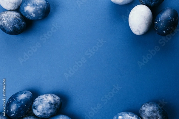 Fototapeta Beautiful group ombre blue Easter eggs with quail eggs and feathers on a blue background. Easter concept. Border eggs. Copy space for text.