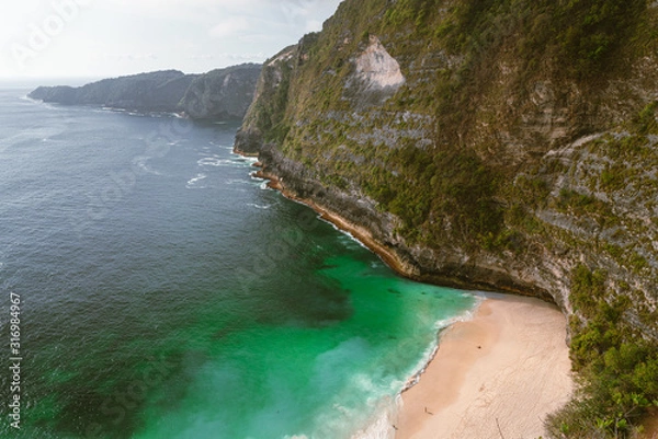 Fototapeta Manta Bay or Kelingking Beach on Nusa Penida Island, Bali, Indonesia. The most beautiful and popular beach with azure water and white sandy beach under new angle of view