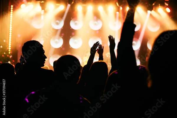 Fototapeta silhouettes of concert crowd in front of bright stage lights