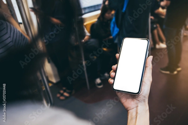 Fototapeta Mockup image blank white screen cell phone.woman hand holding texting using mobile on desk at coffee shop.background empty space for advertise text.people contact marketing business,technology 