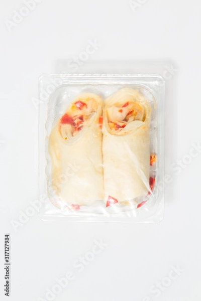 Fototapeta Use less plastic! Two wraps in plastic packaging isolated on white ground. Symbol for environmental pollution done by the food industry