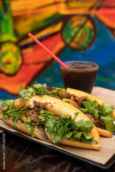 Obraz Vietnamese traditional sandwich, pork Banh-mi with black coffee. Two vietnamese foods on a tray.