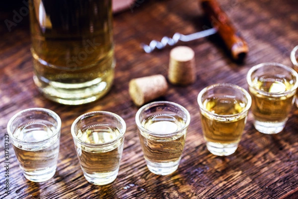 Fototapeta Hand holding glass of alcoholic drinks, cachaça, drips, rum and cognac. Selection of strong and hard alcoholic drinks, glasses. Vodka, cognac, whiskey, grappa, liqueur, vermouth, tincture, rum.