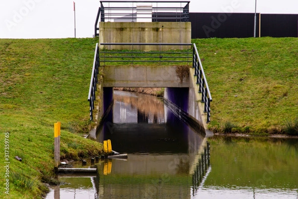 Fototapeta Viaduct over ditch on a winter overcast day in the  Netherlands. Next to the green grass en also used for kano purpose