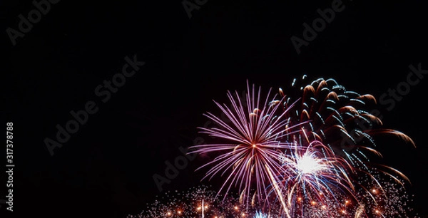 Fototapeta White starburst firework with multiple small gold bursts and red highlights with a black background