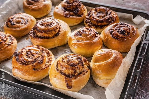 Obraz Close up sweet homemade cinnamon rolls with chocolate cream on a baking sheet