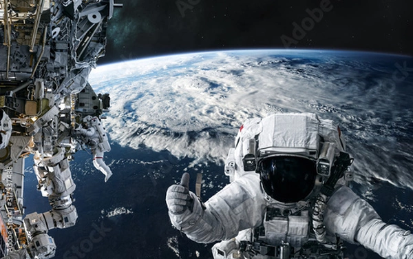 Fototapeta Astronauts and the ISS in orbit of the planet Earth. Solar system. Science fiction. Elements of this image furnished by NASA