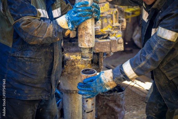 Fototapeta Offshore oil rig worker prepare tool and equipment for perforation oil and gas well at wellhead platform. Making up a drill pipe connection. A view for drill pipe connection from between the stands