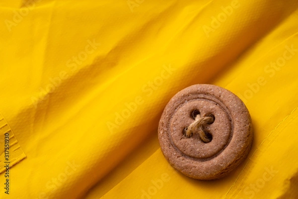 Obraz Cookies button with threads on a yellow cloak.