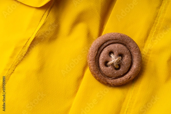 Obraz Cookies button with threads on a yellow cloak.