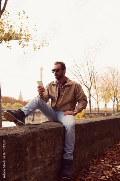Fototapeta Handsome man enjoying in Paris while using cellphone.