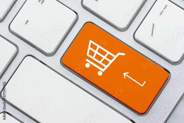 Fototapeta Online shopping / ecommerce and retail sale concept : White basket for checkout, shopping cart symbol on a laptop keyboard, depicts customers order / buy things from retailer sites using the internet