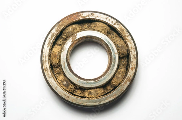 Fototapeta Old and rusty iron ball bearing on white background. Front view. The gap between the balls and the base is clogged with dust, sand and dirt. The concept of timely cleaning of bearings.