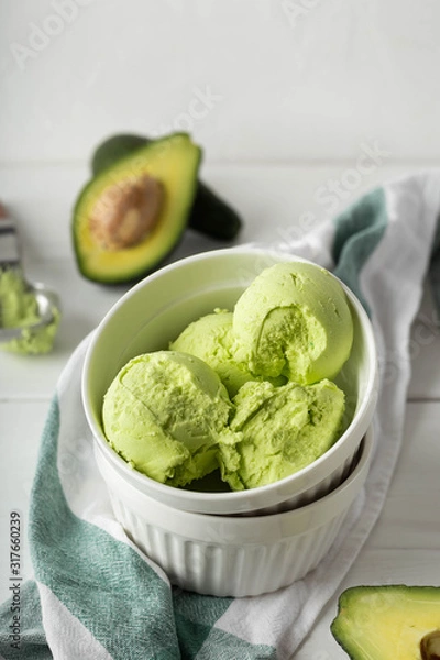 Fototapeta Balls of ice cream from avocado in a white porcelain bowl on a light background. Vertical image and close-up