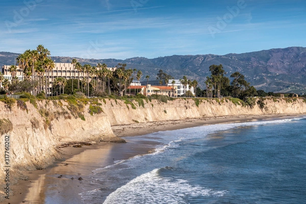 Fototapeta Goleta, CA, USA - January 2, 2020: UCSB, University California Santa Barbara. East side beige cliffs in front of several buildings. Blue ocean in front. Green foliage around. Hills on horizon and blue