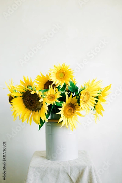 Fototapeta bouquet of bright yellow sunflower flowers in a retro vase on a white background