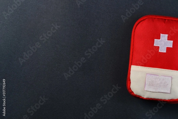 Fototapeta Closed red travel first aid kit pouch on the dark background. Photo with a copy space