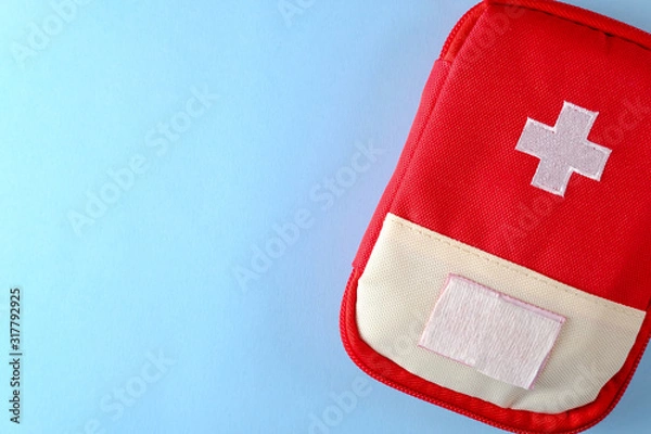 Fototapeta Closed red travel first aid kit pouch on the bright blue background. Photo with a copy space