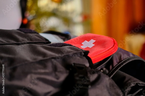 Fototapeta External passport with airplane ticket inside and tourists first aid kit in the pockets of the travel backpack