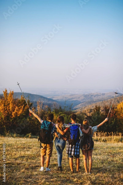 Fototapeta adventure, travel, tourism, hike and people concept - group of smiling friends walking with backpacks in nature