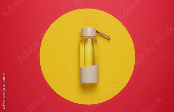 Fototapeta Bottle of water for sports and outdoor activities on red yellow circle background. Top view