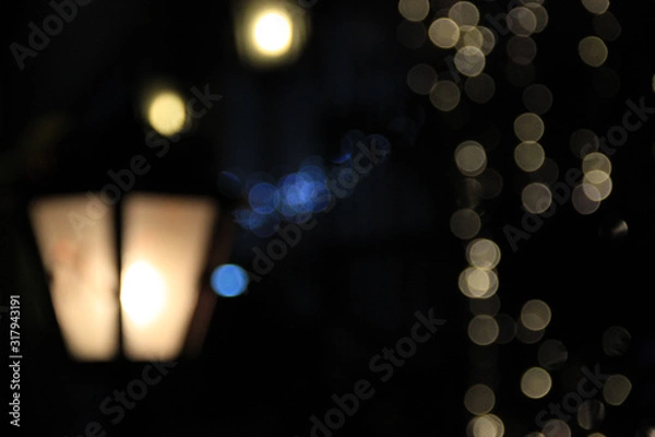 Obraz Blurred lantern out of focus in the street at night in the dark. Yellow and blue lights out of focus. Bokeh. Background. Texture for the design