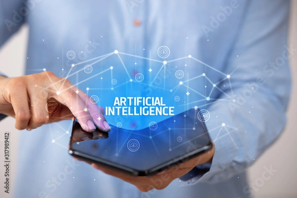 Obraz Businessman holding a foldable smartphone with ARTIFICIAL INTELLIGENCE inscription, new technology concept