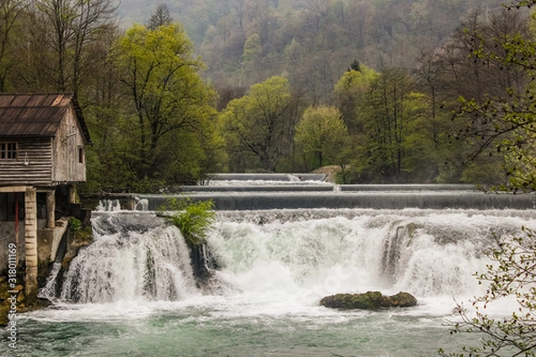 Fototapeta Layered waterfall on the river Una in Bosnia-Herzegovina with a lot of water vapor in the early morning.Dramatic shot of a layered waterfall on the river Una in Bosnia-Herzegovina