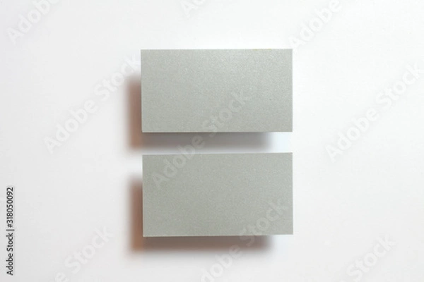 Fototapeta Two silver blank matt textured business cards flying and isolated on white paper background, us standard size 3.5 x 2 inches, real non professional studio photo.