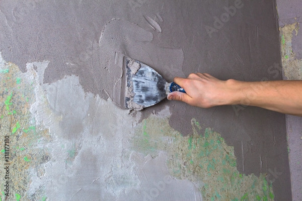 Fototapeta Plaster the wall with a putty knife.Internal construction and finishing works.The Builder puts plaster on the wall.Hand holding a spatula with construction mix and smoothes out bumps.Repair the wall