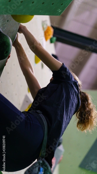 Fototapeta girl bouldering on rocks and grips