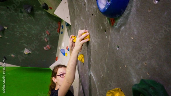 Fototapeta girl bouldering on rocks and grips