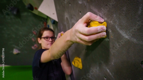 Fototapeta girl bouldering on rocks and grips