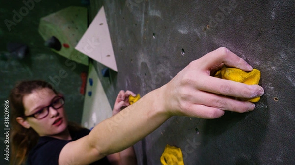 Fototapeta girl bouldering on rocks and grips