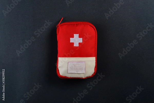 Fototapeta Closed red travel first aid kit pouch on the dark background. Photo with a copy space