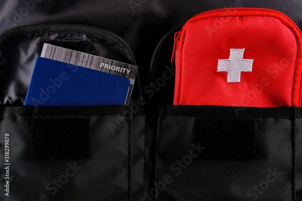 Fototapeta External passport with airplane ticket inside and tourists first aid kit in the pockets of the travel backpack