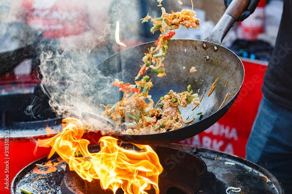 Obraz chef cooks Chinese noodle wok at street food festival