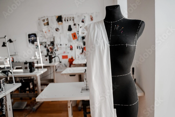 Fototapeta Mannequin with fabric on the shoulder and stuck pins into the fabric in design studio for sewing and tailoring, special education concept