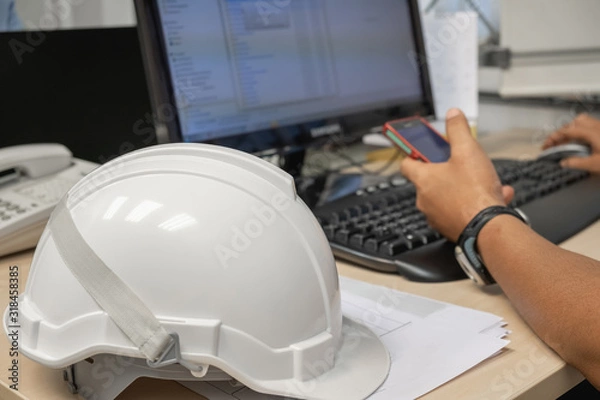 Fototapeta The white industrial helmet is placed in the office and worker background