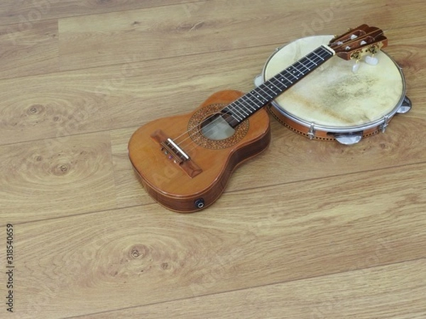 Fototapeta Close-up of two Brazilian musical instruments: cavaquinho and pandeiro (tambourine) on a wooden surface. They are widely used to accompany samba and choro, two popular Brazilian rhythms. Top view.