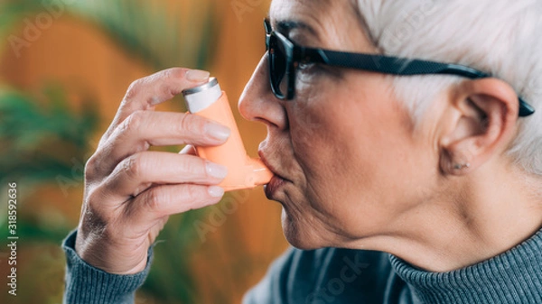Fototapeta Senior Woman Using Asthma Inhaler with Extension Tube