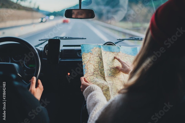 Obraz Happy couple traveling by authentic car in Europe, hipster girl holding touristic map planning route in mountains, lifestyle roadtrip travel concept
