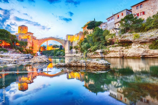 Fototapeta Majestic evening view of Mostar with the Mostar Bridge, houses and minarets, at evening